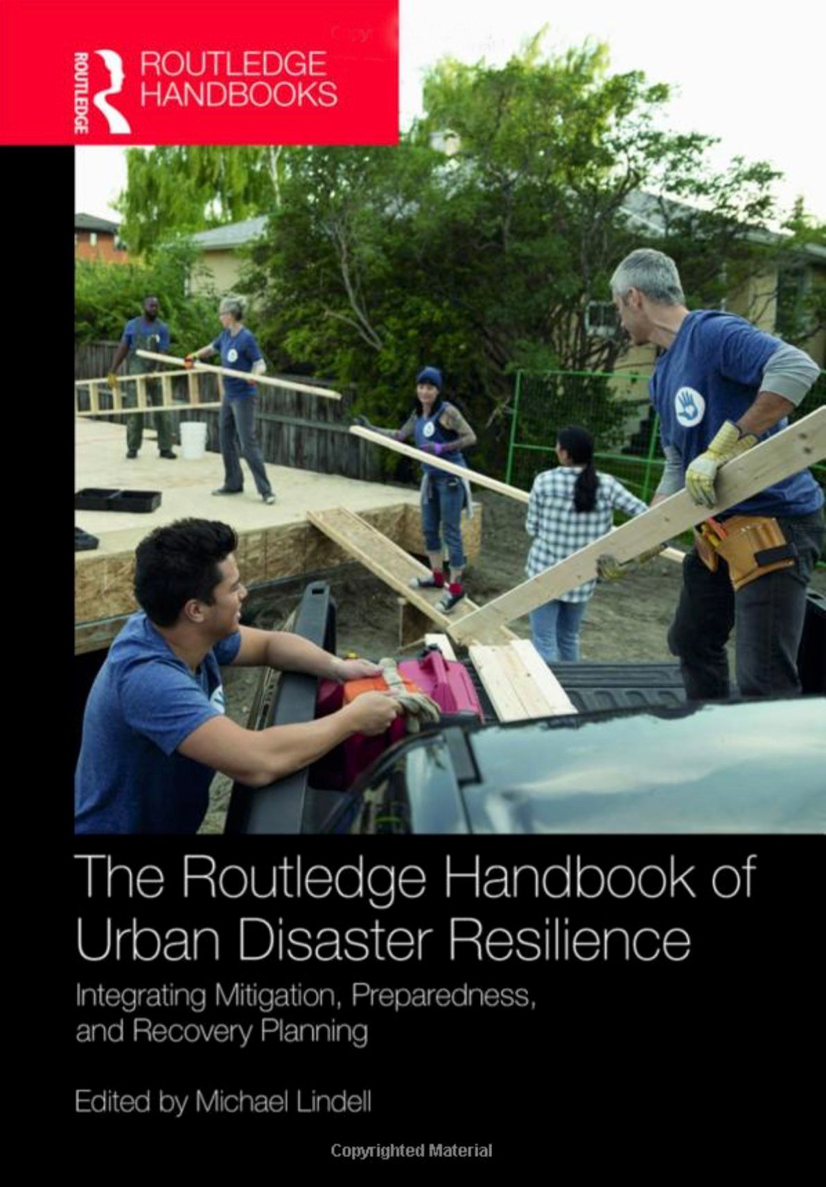 The book cover for "The Routledge Handbook of Urban Disaster Resilience" features a team unloaded planks of wood from the back of a truck.