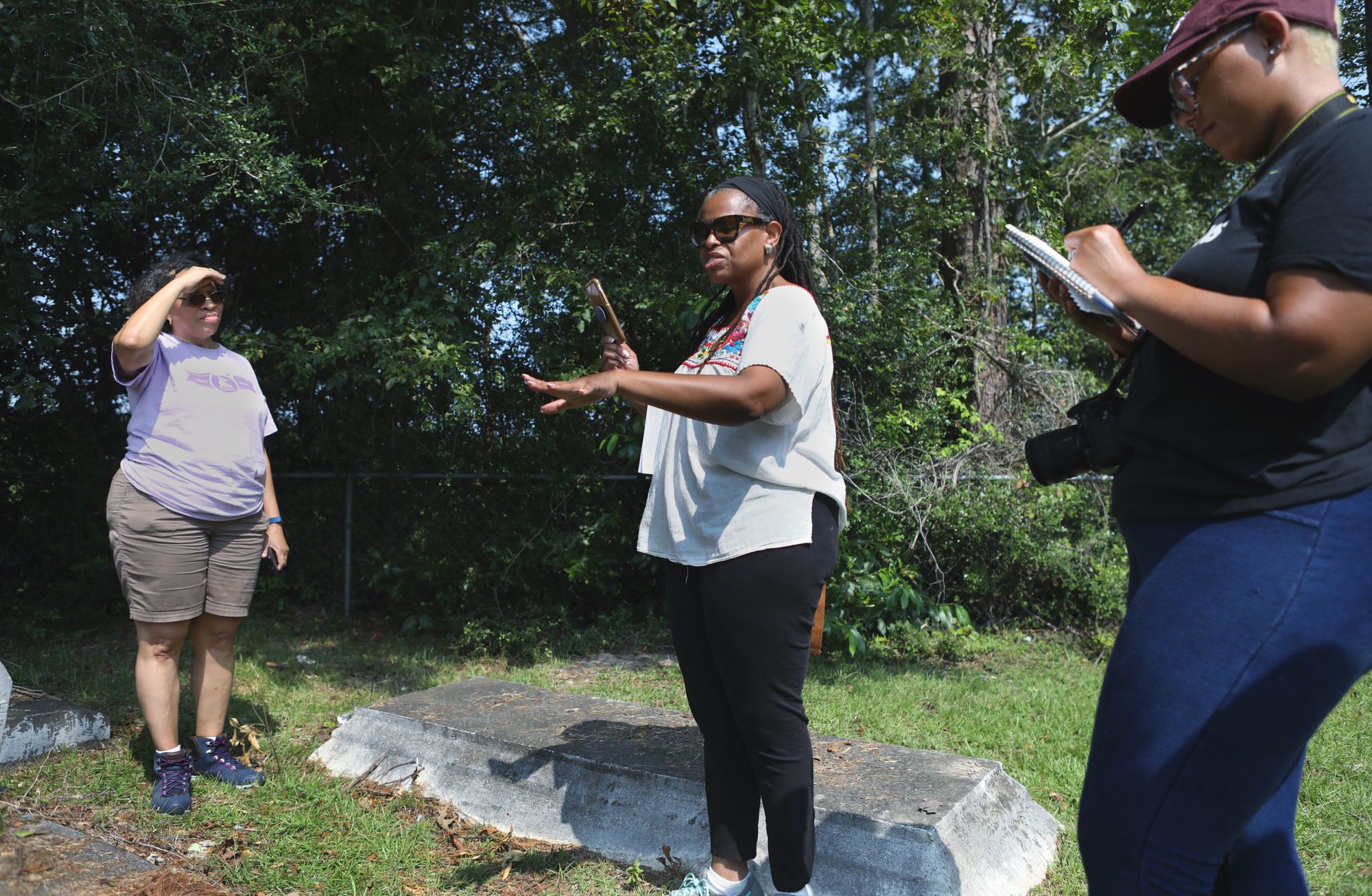 Three women at a cemetery in a wooded area