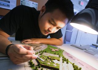Student works on small architecture model under lamplight
