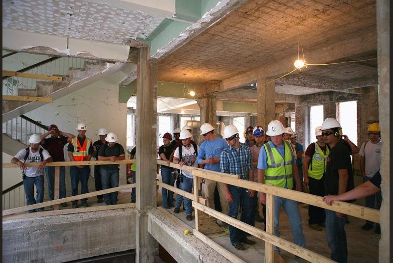 Students wearing hard hats tour Francis Hall during renovations