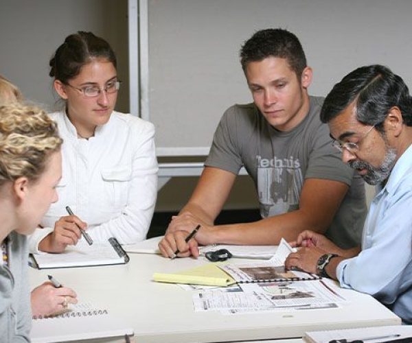 Students and a professor collaborate at a table