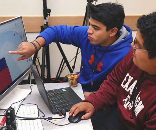 High school students work on design plans from a computer in a studio