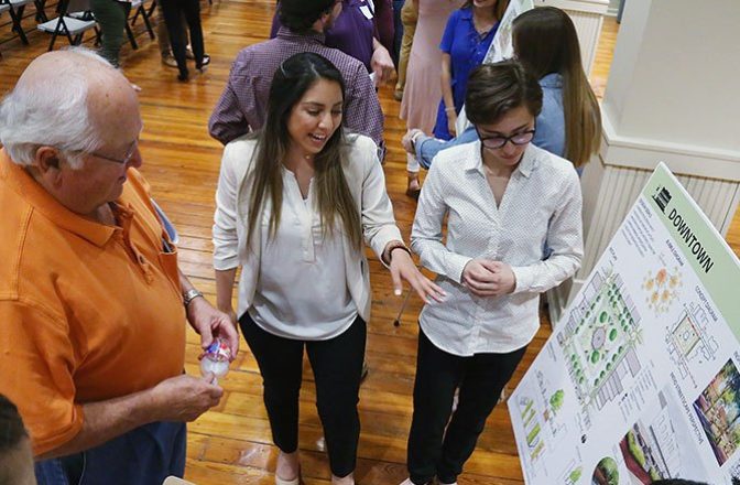 Two students present downtown project development plans to a community member during an open forum