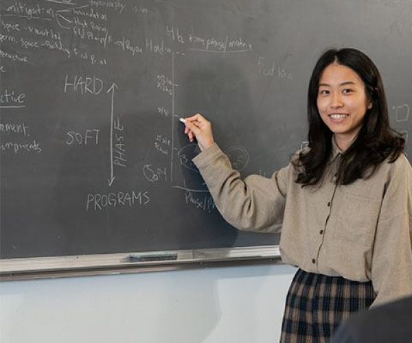 A student writes and presents her work on a chalkboard