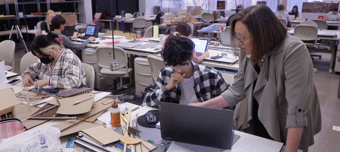 A professor works with a student in a studio