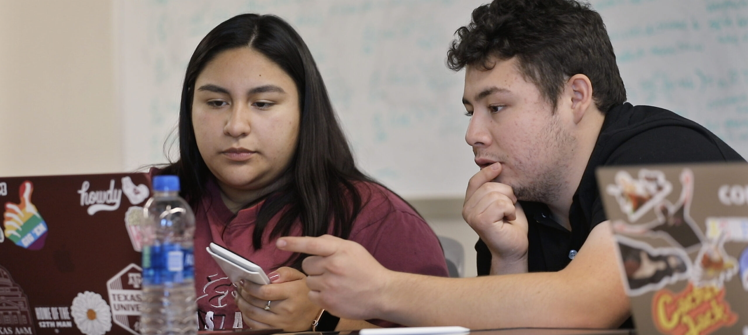 Two students work at a shared laptop