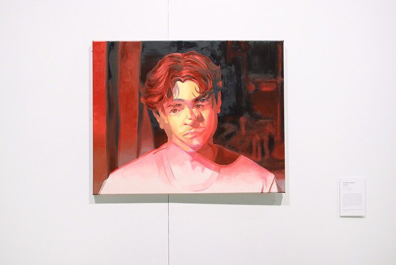 A close up photograph of a self portrait painting painted with various hues & shades of red.
