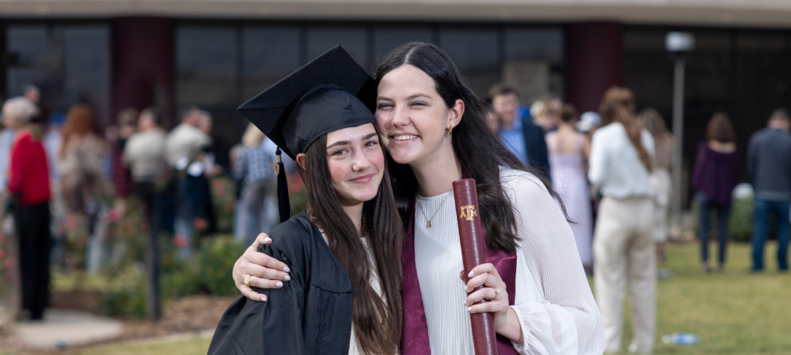 two graduates hug