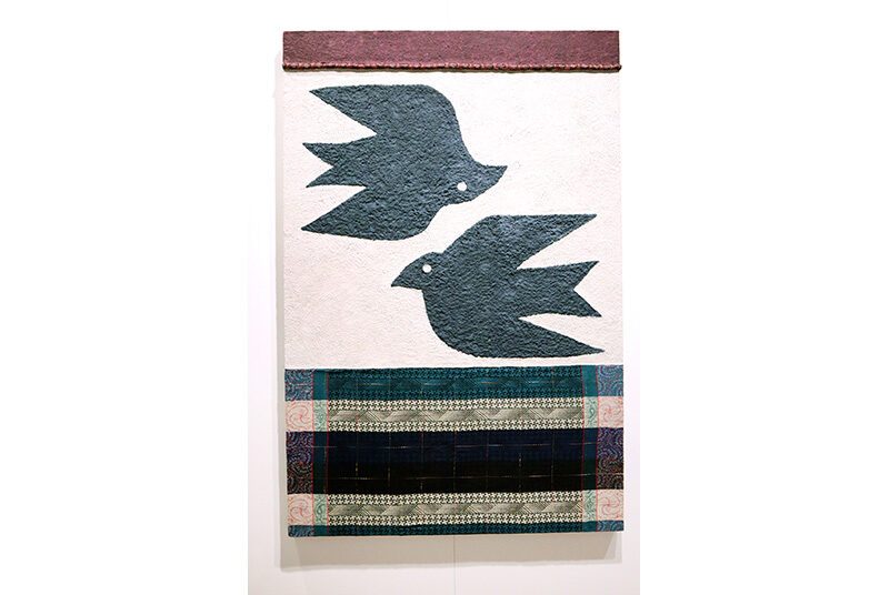 A view of one of Jenn Hassin’s artworks showing two black birds with bands of fabric at the top and bottom.