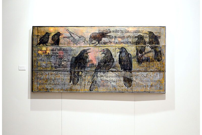 A view of one artwork with 8 black birds and one white bird sitting on wires.