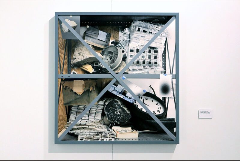 A view of one of Bryan Florentin’s artworks showing objects having fallen off of the shelf and crashed into one another.
