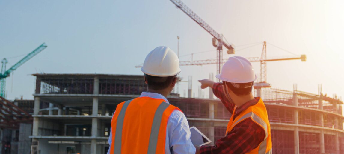 Two people using the tablet for discussion and working at construction on site