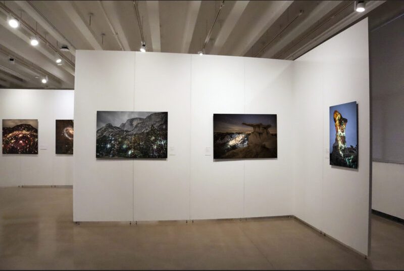 In the foreground, there are 3 medium sized artworks installed on the gallery wall. In the background towards the left, there are 2 square photographs on the wall.