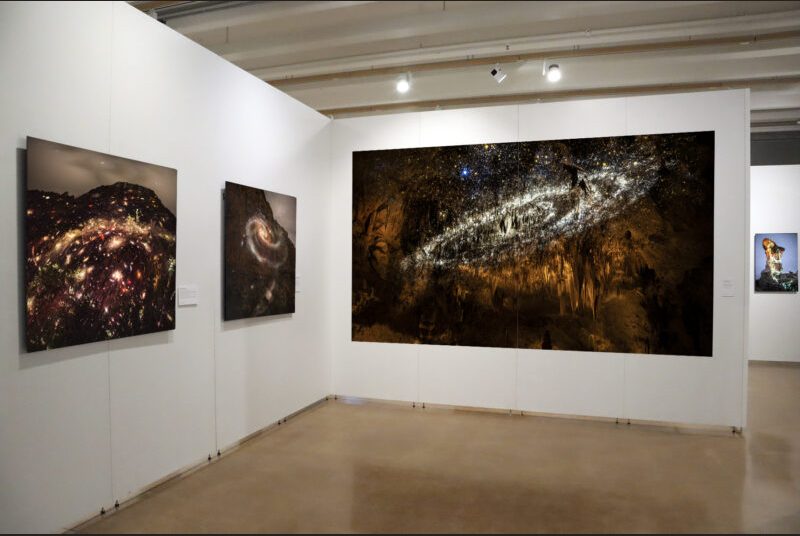 A large-scale photograph with the Mily Way project on Carlsbad Cavern is on the right. On the left, there are two additional artworks installed on the gallery walls.