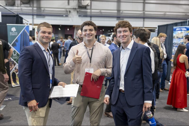 A group of three students smile for the camera.