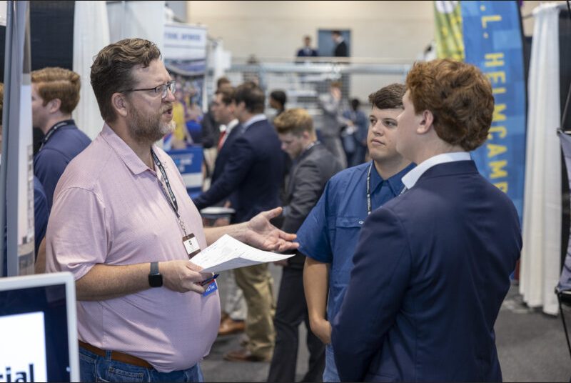 Two students listen to a recruiter speak.