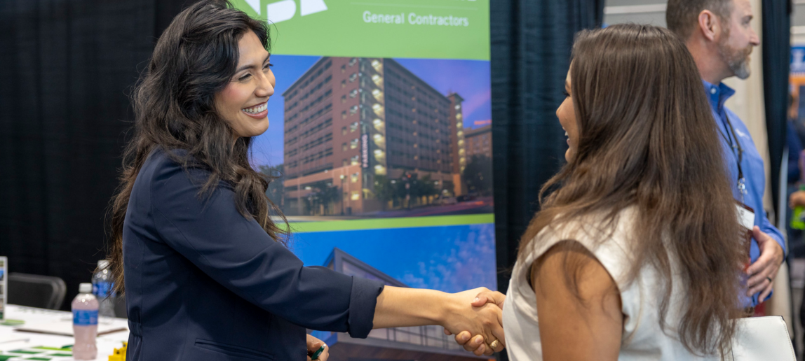 Two people shaking hands at a career fair.