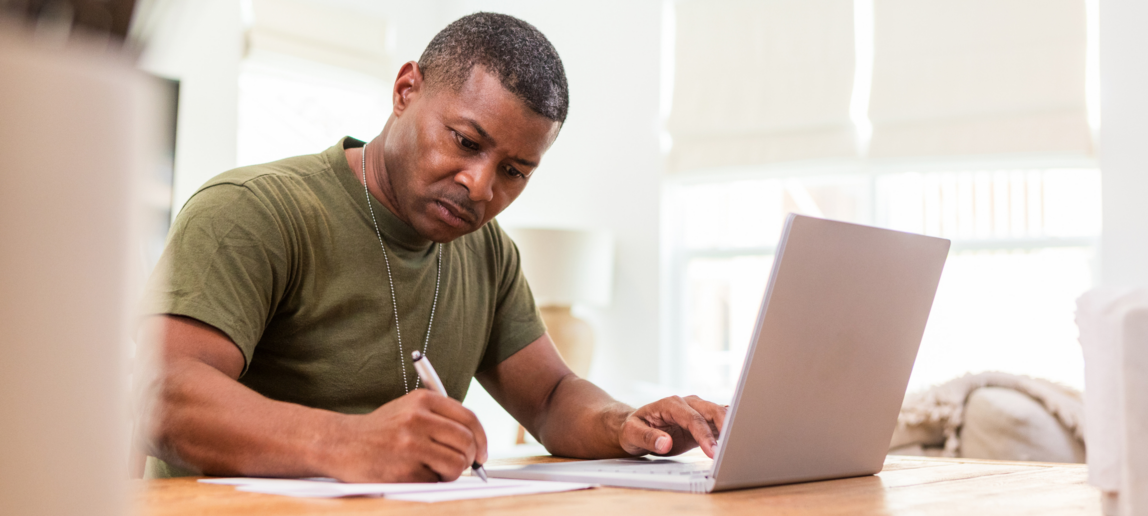 Working at home, the serious mature adult soldier takes continuing education courses online using his laptop.