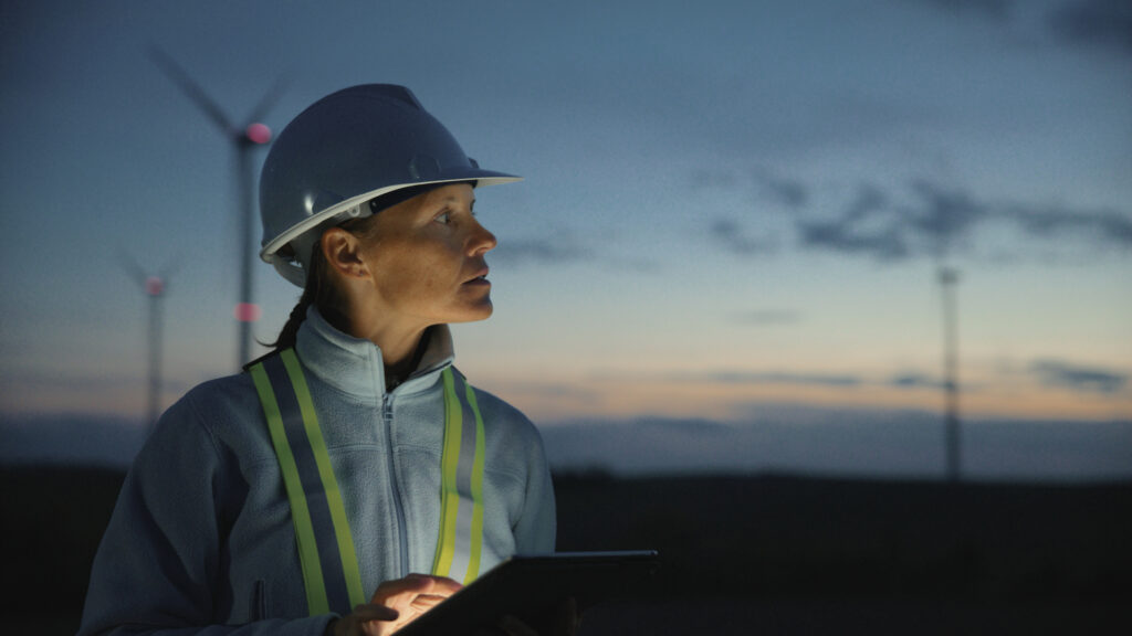 Woman Engineer in Work Attire Utilizing Digital Tablet,Meticulously Inspecting Wind Turbines at Rural Farm,