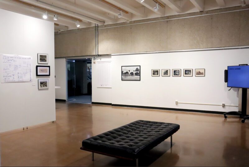 A view of the art gallery with a artworks on the wall and a large black sofa in the center.