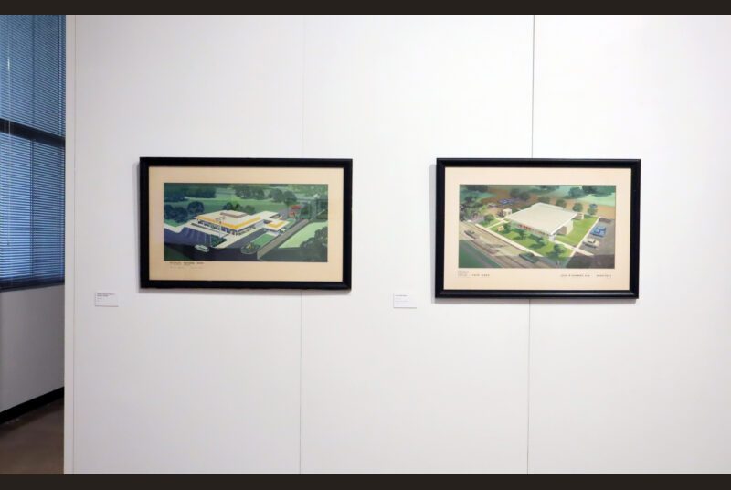 Two colorful paintings of buildings showing an aerial view are on the wall.