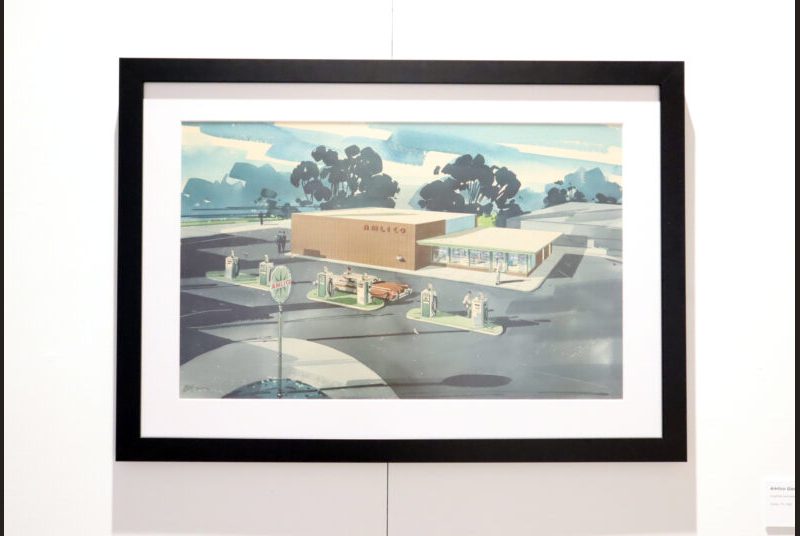 A colorful painting of a gas station is hanging on the wall.