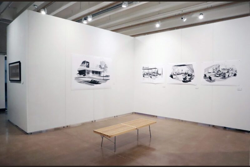 A large black and white painting of a bank on the left. In the center, 3 smaller paintings of the interior of the same bank are lined up. There is a wooden bench in the center of the gallery. An artwork is on the wall towards the background on the left.