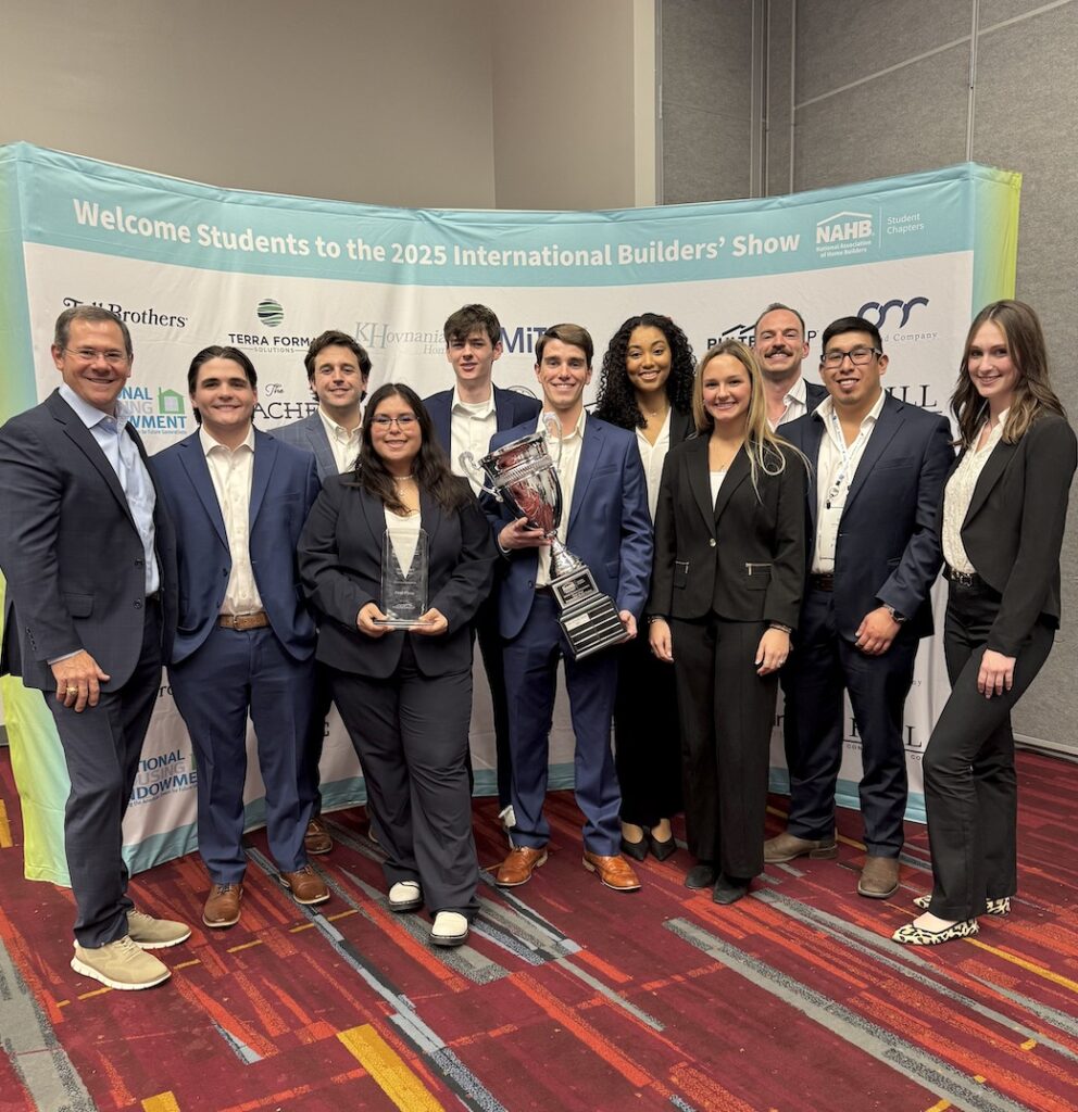 Ten students and one faculty member posing with a trophy.