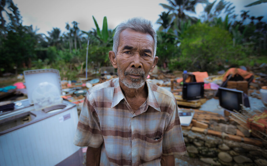 Flood victims stand next to a destroyed home.