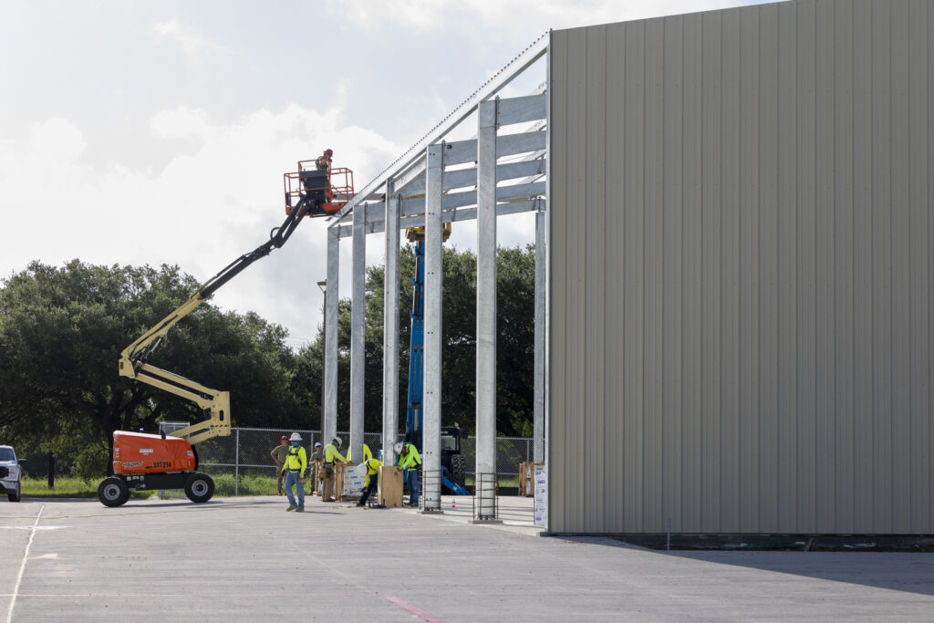 Construction workers assemble the steel columns and roof of the Construction Field Lab.