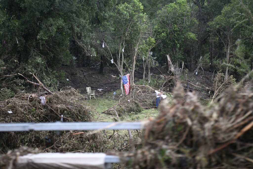 Debris and broken tree branches scattered across a wooded area after a flood in Central Texas.