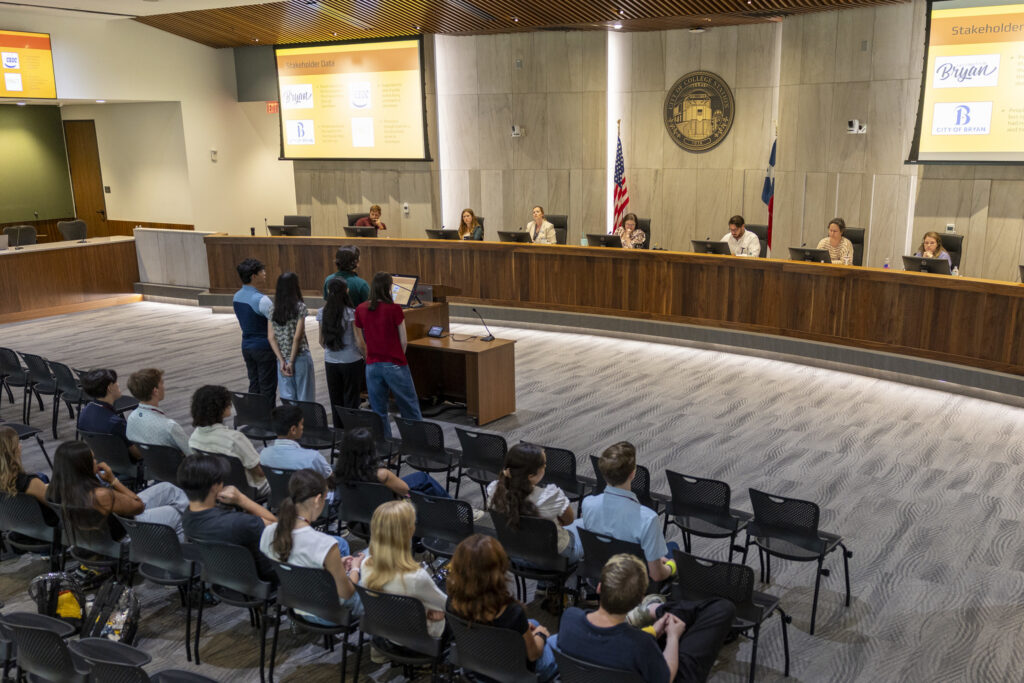 A group of students stand behind a podium to present to city planners.