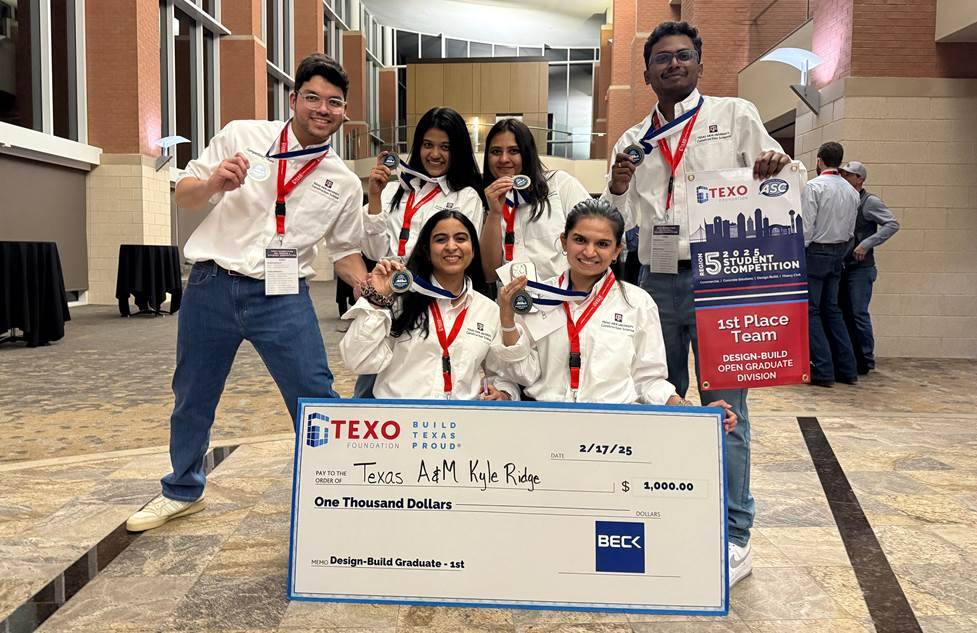 Six students holding a large check and wearing medals after winning a competition