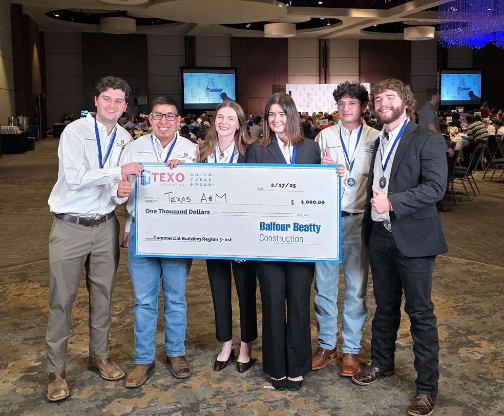 Six students holding a large check after winning a competition